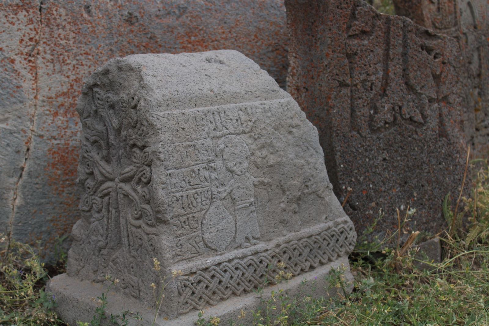 Ancient carved cross-stone beside weathered inscribed stones