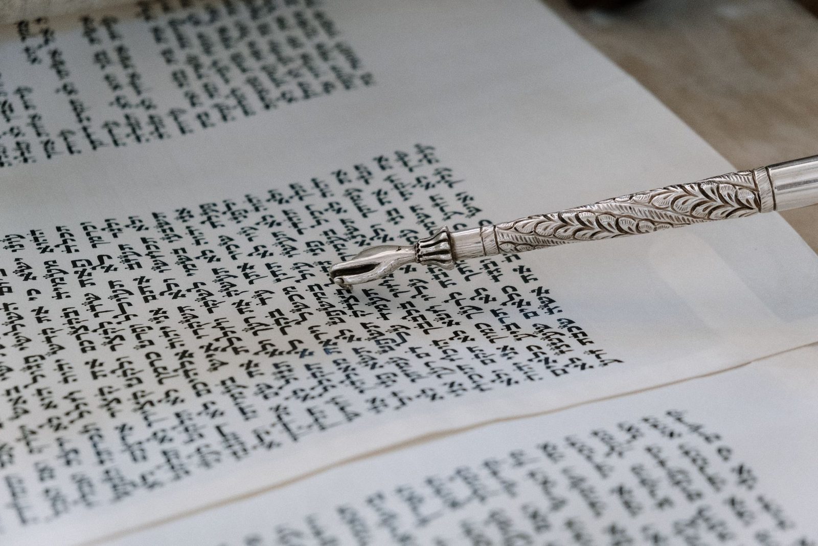 Silver yad pointer resting on the Hebrew text of an open Torah scroll